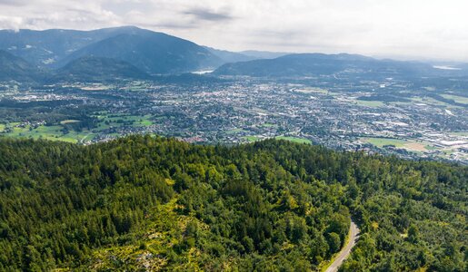 Luftaufnahme der Straße mit Wald und Bergen und Villach im Hintergrund | © villacher-alpenstrasse.at/Stabentheiner