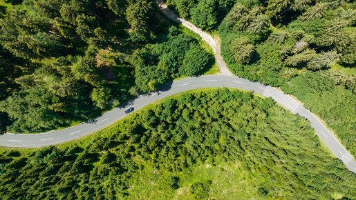 Luftaufnahme der Straße mit Wald und schwarzes Auto | © villacher-alpenstrasse.at/Stabentheiner